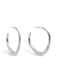 Pendientes de aro de plata con un diseño retorcido. La textura es suave, presentando una silueta abierta y un acabado pulido y reflectante.