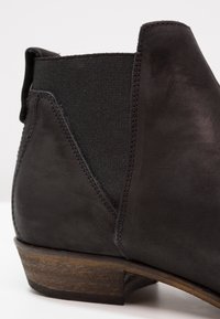 Nahaufnahme eines schwarzen Leder-Chelsea-Boots mit Ferse, elastischem Seitenpanel und Holzsohle.