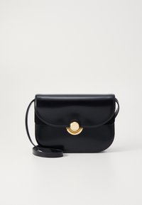Borsa a mano in pelle nera con finitura liscia, hardware circolare dorato e tracolla rimovibile. Presenta una chiusura a patta con bordi arrotondati.