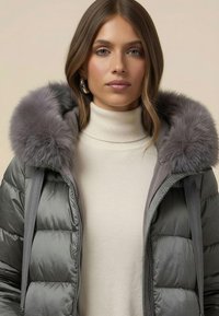 Šedá prošívaná bunda s kapucí lemovanou kožešinou. Má vysoký límec a zapínání na zip s bočními kapsami. Nositelná přes béžový rolák.