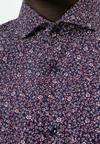 Marinblå blommig skjorta med röda och vita mönster, som har en klassisk krage, knappstängning och en mjuk tygkänsla.