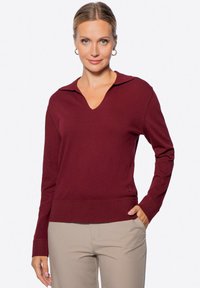 Burgunderfarbener Pullover mit langen Ärmeln, V-Ausschnitt und Kragen-Details, geripptem Saum und glatter Textur, kombiniert mit beigen Hosen.
