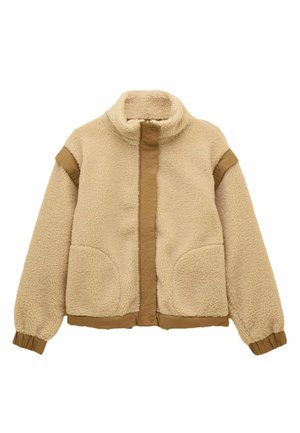 Veste en polaire sherpa beige avec col haut, fermeture éclair frontale, bouton-pression, deux poches avant et bordure marron aux poignets et aux épaules.