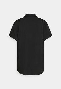 Chemise noire à manches courtes avec col classique, montrée de dos sur un fond clair uni.