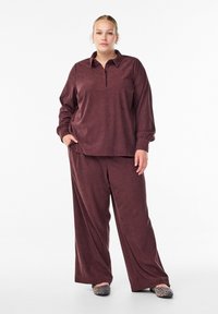 Divdaļīgs mājas apģērba komplekts bordo krāsā, kas sastāv no krekla ar apkakli un pogu aizdari, kā arī platām biksēm. Mīksts audums ar teksturētu apdari.