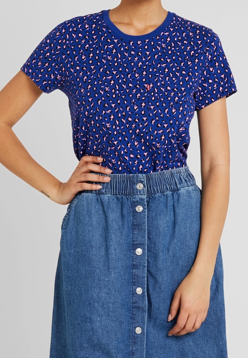 Blue short-sleeve t-shirt with a pink and black leopard print, paired with a denim skirt featuring a button-up front and elastic waistband.