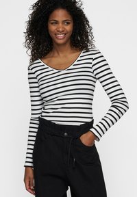 Maglietta a maniche lunghe a righe bianche e nere, con texture a costine, design a V, abbinata a pantaloni neri a vita alta con cintura con cordoncino.
