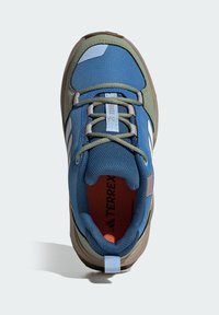 Μπλε και πράσινο παπούτσι πεζοπορίας με υφασμάτινο επάνω μέρος, επενδεδυμένο γιακά και λαστιχένια σόλα. Διαθέτει λευκές ρίγες και κόκκινο εσωτερικό με θηλιά έλξης.