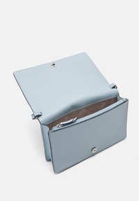 Borsa in pelle azzurro chiaro con patta frontale aperta, che mostra una tasca interna con zip e foderatura beige con motivo stampato.