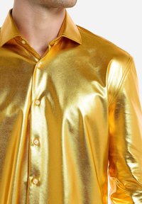 Kuldne metallik pika varrukaga särk, millel on sile ja läikiv tekstuur, terav krae ning ees viis nupuvajutust sulgemiseks.
