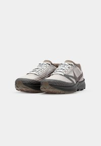 Chaussures de trail avec une tige en mesh gris clair, accents gris foncé, design texturé et une semelle noire robuste pour l'adhérence.