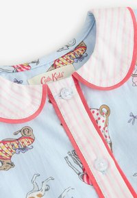 Otro kratek otrok s roza in belimi črtami ter rdečim robom, svetlo modra tkanina z igrivimi vzorci psov, ki nosijo kopalke.