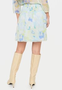 Kukkakuvioinen, läpikuultava mini hame pastellisävyissä, jossa on rypytetty vyötärö. Yhdistetty polvipituisilla beigenvärisillä nahkabootseilla.