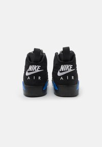 Tenisi negri cu un superior din suede, cu accente albastre, logo-uri Nike embossate în alb pe călcâi și o talpă solidă din cauciuc negru.