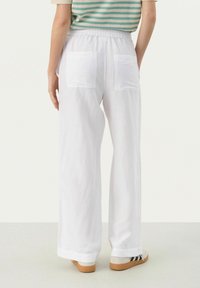 Pantalons blancs à larges jambes en tissu léger avec une taille élastique et deux poches arrière. Les ourlets sont légèrement retroussés.