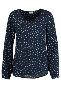 Blouse marine à manches longues, col en V et un motif circulaire bleu clair dispersé. Fabriquée en tissu léger ; ourlet courbé au bas.