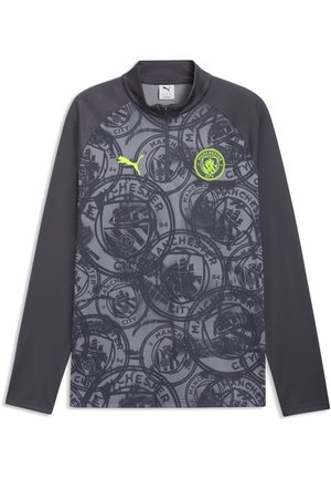 Camiseta deportiva de manga larga de color gris oscuro del Manchester City con patrón repetido del escudo del club, logo de Puma en amarillo neón y cuello con cremallera hasta un cuarto.