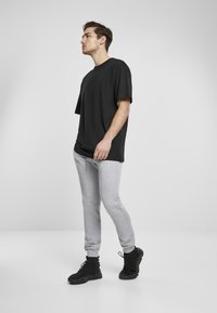 Svart kortärmad t-shirt, grå tapered sweatpants och svarta träningsskor. Outfitten har en avslappnad passform med en enkel design.