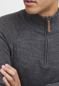 Maglione grigio con zip al collo, colletto a costine, texture morbida e cuciture dettagliate. Il tirazip presenta un accento in pelle con l'iscrizione "BLEND".