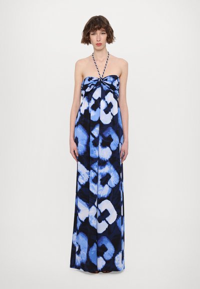 Robe maxi avec un col halter dans un motif abstrait bleu et noir, présentant un détail noué à l'avant et un tissu fluide et léger.