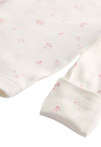 Witte longsleeve top van zachte stof met een bloemenpatroon in roze en geel. Heeft roze mouwafwerkingen en een ronde halslijn.