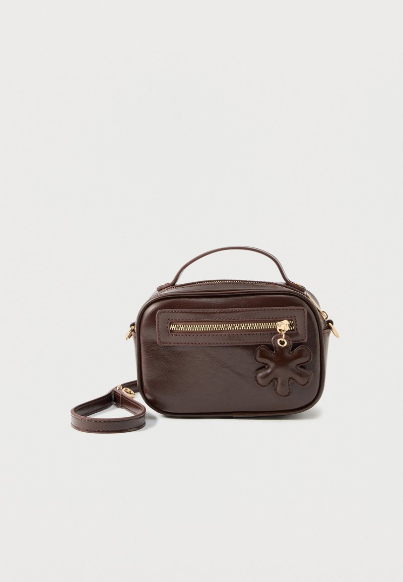 Sac bandoulière rectangulaire en cuir marron foncé avec une poignée supérieure, une poche avant zippée et un charm en cuir en forme de fleur sur la tirette du zip.