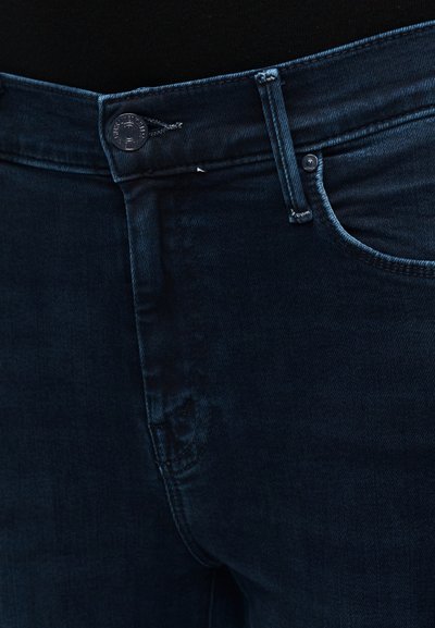 Tumesinised teksapüksid, millel on sile pind, ees nööpide kinnitussüsteem, vööaasad ja tavaline viie taskuga disain.