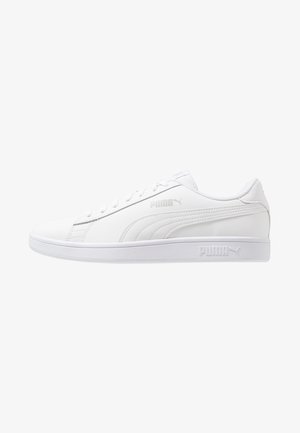 Zapatilla blanca Puma de perfil bajo con diseño de cordones, franja lateral con marca y logo en relieve en la suela y la parte superior sobre un fondo blanco.