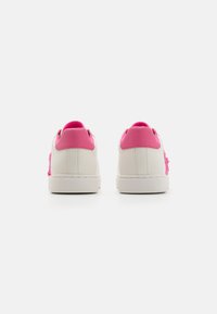 White sneakers with pink accents, featuring a textured pink design on the sides, and a smooth pink collar. Flat sole, simple design.