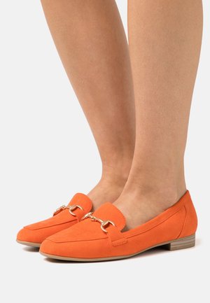 Mocassins en daim orange avec un accent en chaîne dorée, présentant un petit talon carré et un design à bout rond. Texture lisse et détails de couture minimaux.