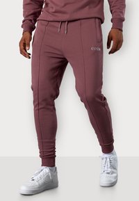 Bordeauxfarbene Jogginghosen aus weichem Stoff, mit elastischem Bund und Kordelzug, schmal zulaufenden Beinen und weißer „ESTEEM“-Stickerei an der Seite.