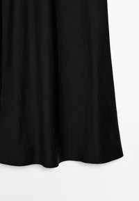 Jupe en tissu noir lisse suspendue droite avec de légers plis au bord inférieur sur un fond blanc uni.