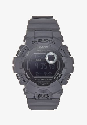 Reloj G-Shock gris con pantalla digital, correa de goma, múltiples botones, resistente al agua hasta 20 bares y conectividad Bluetooth.