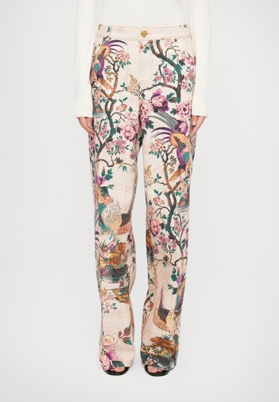 Pantalons larges à motif floral en beige clair, ornés d'oiseaux colorés, d'arbres et de fleurs. Le tissu a une apparence texturée.