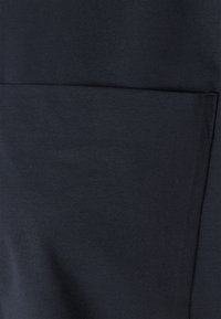 Dunkelmarineblaues Gewebe mit einer glatten Textur und einer großen, horizontalen Tasche. Das Material wirkt weich und flexibel.