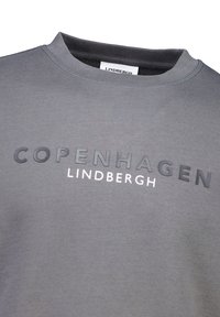 Sudadera gris con cuello redondo acanalado, con el texto en relieve "COPENHAGUEN" y el texto impreso "LINDBERGH" en blanco y negro. Textura suave.