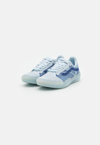 Sapatilhas azul-claro com uma mistura de materiais em camurça e malha, com um design texturizado, atacadores planos e uma sola semi-translúcida.