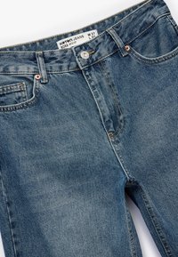 Niebieskie d�żinsy o kroju z lat 90., z guzikowym zapięciem, kontrastowym przeszyciem i subtelnym efektem wytarcia na materiale. Rozmiar W 27, L 32.