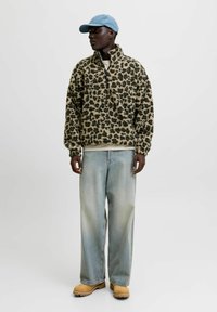 Fleece pullover med leopardprintmønster, høj krave og lange ærmer. Sammen med lyseblå, vide jeans og brune støvler.