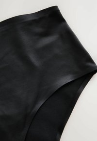 Indumento in tessuto nero a vita alta con una texture liscia e opaca e linee pulite, caratterizzato da un orlo curvo e senza hardware visibile.