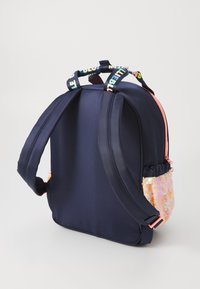Marinblå tygryggsäck med en sidoficka med paljetter i rosa och ljusa handtag. Har justerbara axelremmar och ett blixtlåsförsett huvudfack.