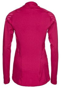 Maglia a maniche lunghe aderente di colore rosa acceso, realizzata in tessuto traspirante, con collo alto e dettagli testurizzati sulle spalle.