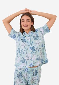Kortärmad, knappupp skjorta och matchande shorts i ljusblått, med ett blommönster i mörkare blått och vitt på mjuk tyg.