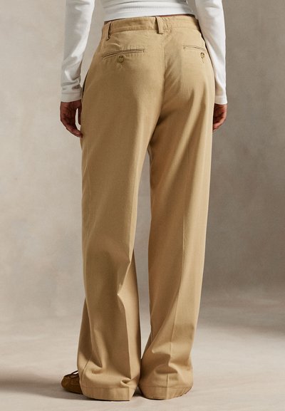 Beige broek met wijde pijpen, gemaakt van een gladde stof, met achterzakken en knopen, en een losse pasvorm.