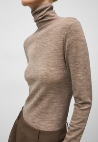 Brązowy sweter z golfem w delikatnym splocie, o dopasowanej sylwetce i długich rękawach. Wykończony gładką, lekko błyszczącą powierzchnią.