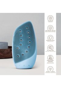 Siliconansiktstvätt i ljusblått, med texturerad yta med prickar och integrerade kontroller. Vattentålig och magnetiskt laddningsbar.