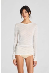 Maglietta bianca a maniche lunghe, leggera, con motivo a rombi, scollo rotondo e stile aderente. Il materiale appare trasparente con una texture liscia.