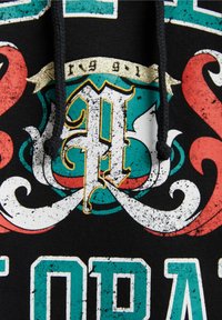 Felpa nera con cappuccio caratterizzata da grafiche vibranti e consumate in rosso e teal, con lettere bianche testurizzate e un emblema decorativo con dettagli dorati.