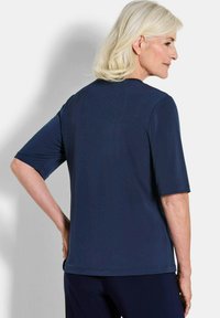 Navyblaues Kurzarm-Oberteil mit geradem Schnitt und runder Halslinie, von hinten gezeigt. Glatte Stoffoberfläche ohne Muster oder Verzierungen.