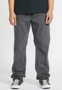 Vaqueros de mezclilla gris con un diseño de pierna recta, que presentan una textura sutil y costuras en contraste, combinados con zapatillas negras de corte bajo.